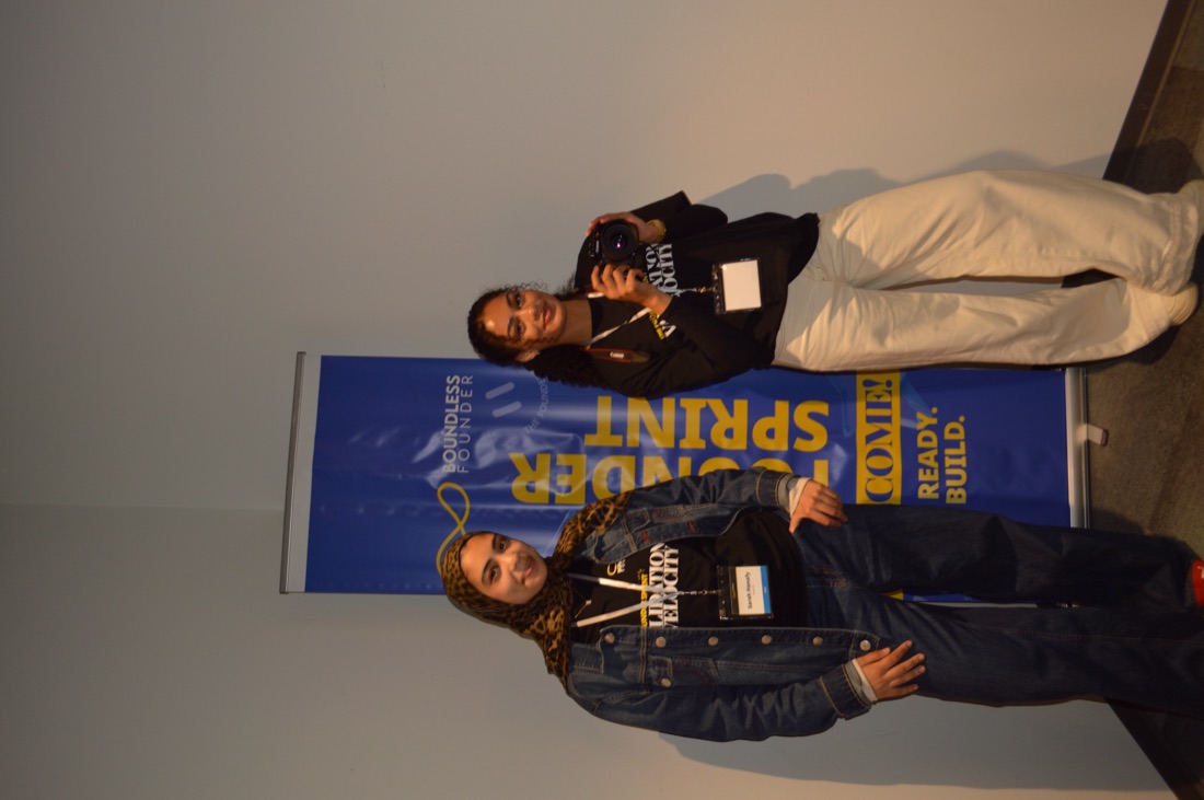 Two Founder Sprint crew members by the “Ready. Build.” welcome banner.
